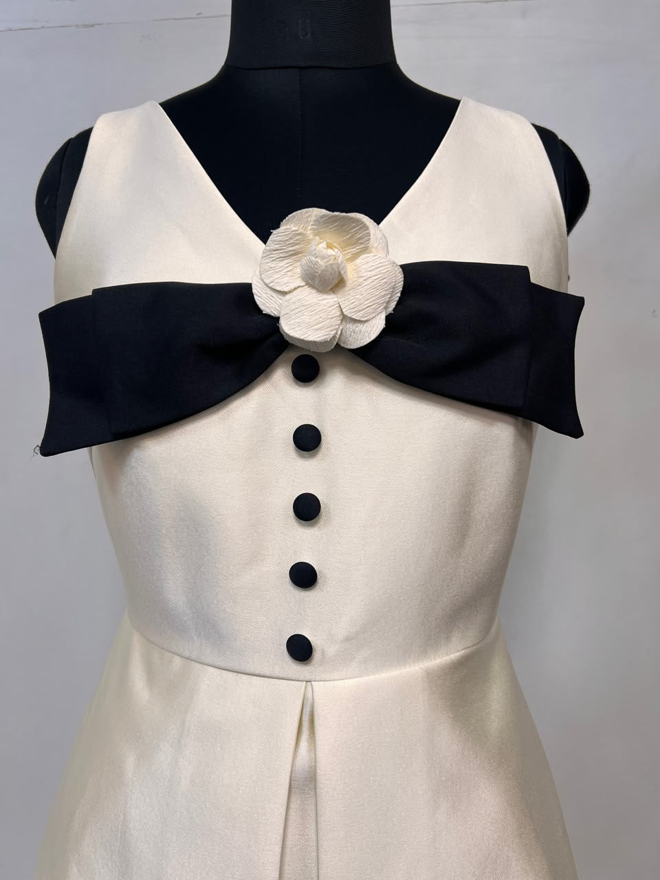 Cream-white dress bodice with black off-shoulder bow and white flower brooch